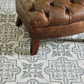 Brown tufted leather ottoman with wooden legs in pentillie dark grey on grey setting