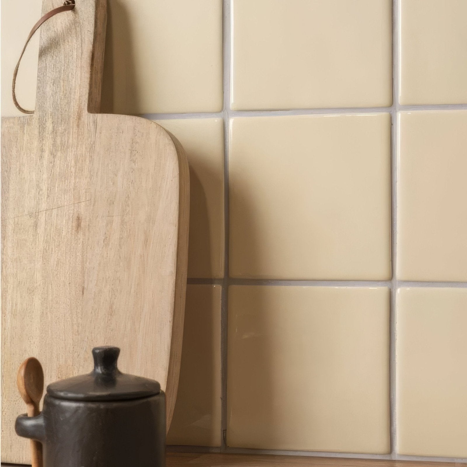 A rustic wooden cutting board with natural grain and leather loop handle in peridot field tile design