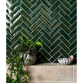 Petite porcelain gloss green dark green glossy rectangular tiles arranged in a herringbone pattern with white grout