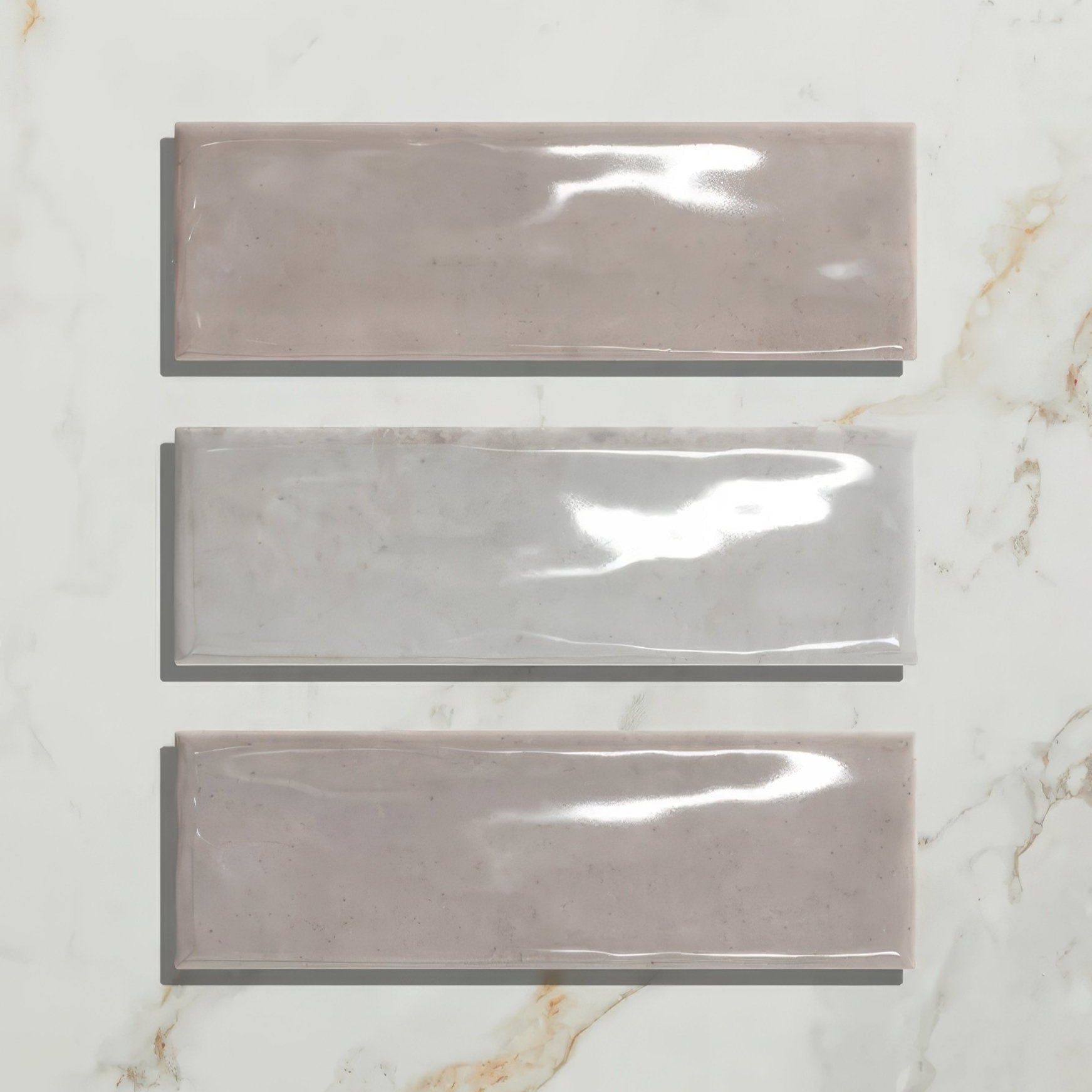 Three rectangular glossy porcelain gloss pearl tiles in muted taupe and gray tones arranged vertically on marble