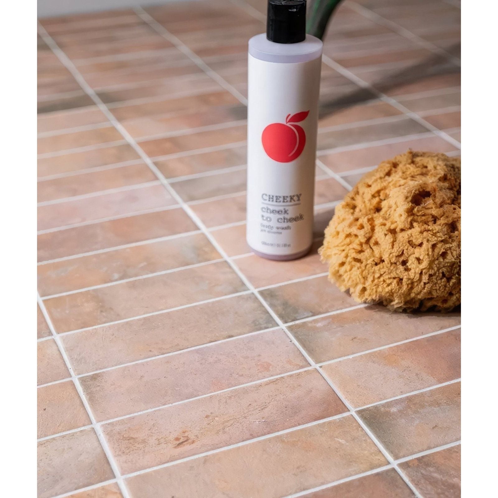 White bottle with black cap and red apple logo labeled cheeky cheek to cheek body wash petite porcelain matt cotto dark