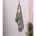 A petite porcelain matt white towel in olive green and white stripes with textured weave hanging from a hook