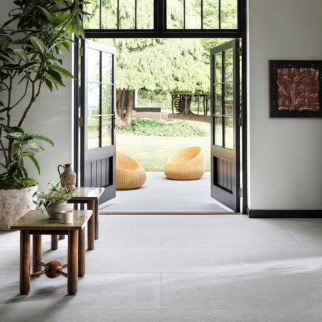 Two mustard-yellow wicker lounge chairs on a light gray tiled floor by open black-framed glass doors in Piazza Bone 60 x 120cm