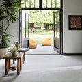 Two mustard-yellow wicker lounge chairs on a light gray tiled floor by open black-framed glass doors in Piazza Bone 60 x 120cm