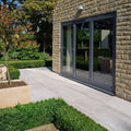 Modern gray aluminum-framed sliding glass doors set into a stone exterior wall showcasing pierre porcelain paving gris