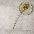 A dried goldenbrown thistle on a pale green pierre porcelain paving gris plate with blue floral patterns