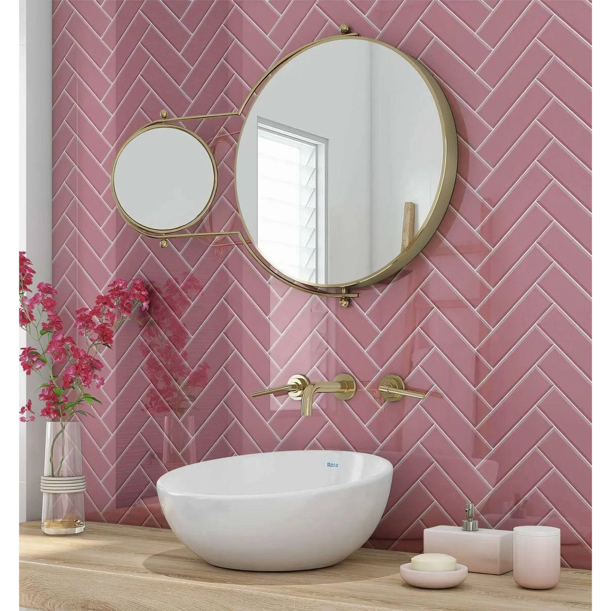 White ceramic bowl sink with gold-toned faucet against pink herringbone tile backsplash in pink herringbone shower panel
