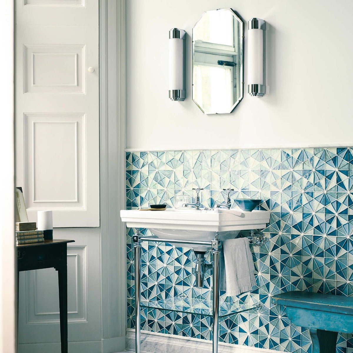 White ceramic pedestal sink with chrome legs and towel hanging from the side in platinum pale finish