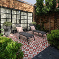 Black metal-framed brompton porcelain clarence lounge chairs with dark gray fabric cushions and light pink throw pillows