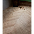 Beige wood-grain patterned davos chevron porcelain matt floor tiles arranged in a herringbone layout