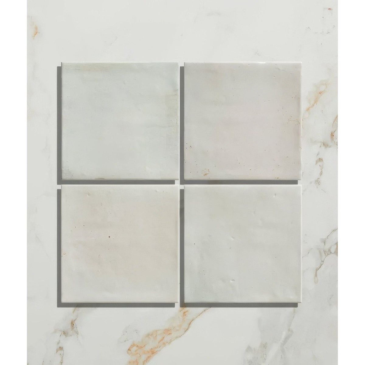 Four light gray marble ceramic tiles with subtle veining arranged in a grid for hammam ceramic blue collection