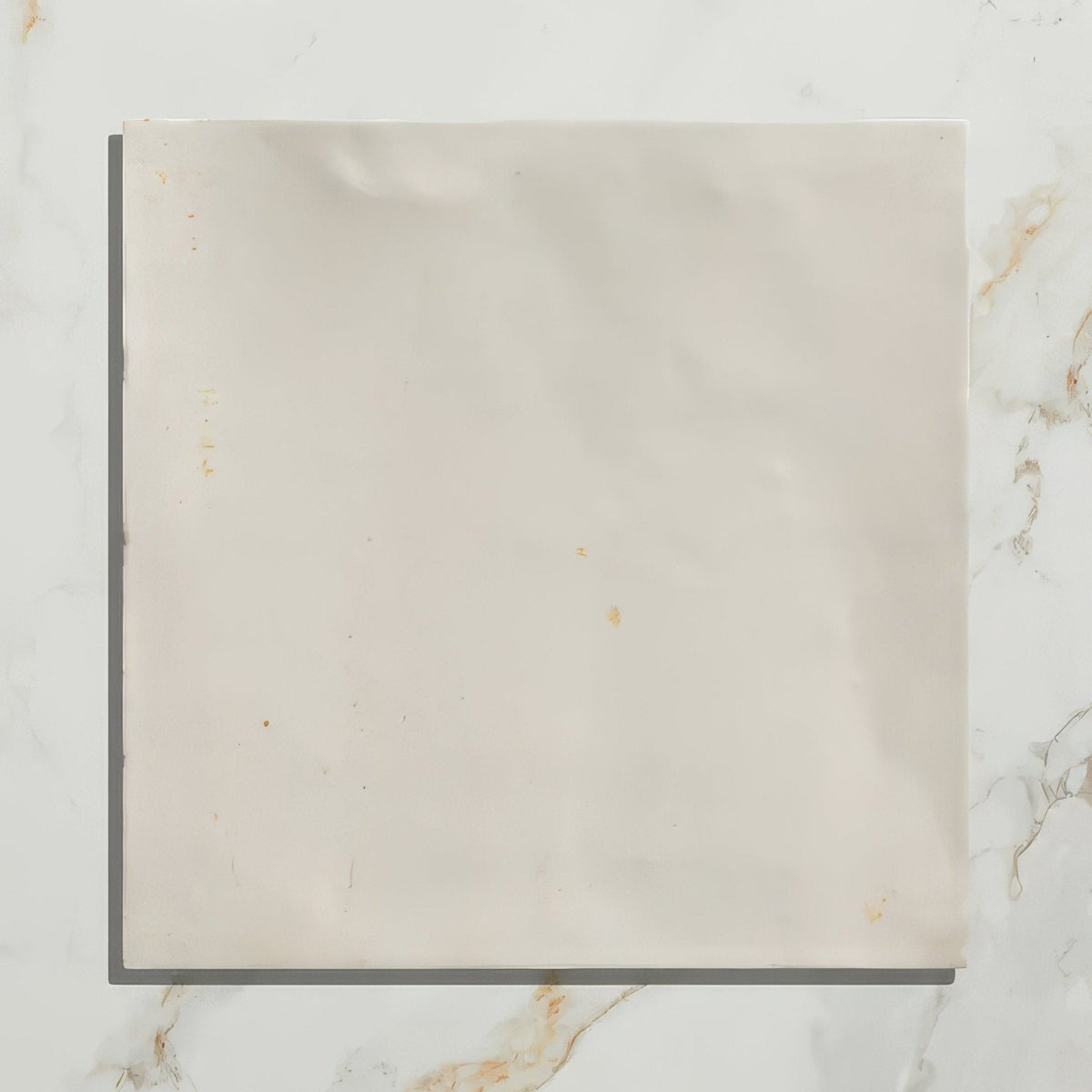 A square off-white hammam ceramic white tile with subtle marbling and minor surface stains on a ceramic material