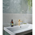 illusion Whisper Onyx Porcelain Polished Mist white marble-effect tiles with a gold tap and sink