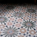 Levante ceramic matt patterned floor tiles with repeating floral design in muted pink gray and black on white background
