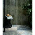 A black woven rattan stool with a green and white patterned towel draped over it from lombok porcelain moss collection