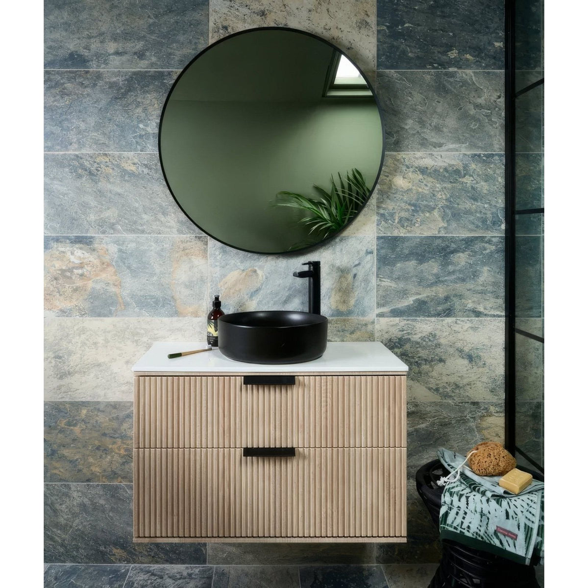 Black ceramic vessel sink with sleek modern design on light wood vanity with vertical slats and black handles lombok porcelain moss