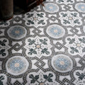 Orleans ceramic matt vintage-style mosaic floor tiles with intricate black gray and muted blue floral patterns on white