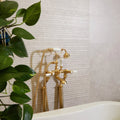 Riverside Wall Ceramic Linear Perla white ceramic tiles with a gold bathtub tap and showerhead