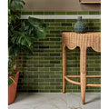 Soprano Porcelain 60 x 120cm cream marble-effect tiles with a green ceramic vase on a wicker table