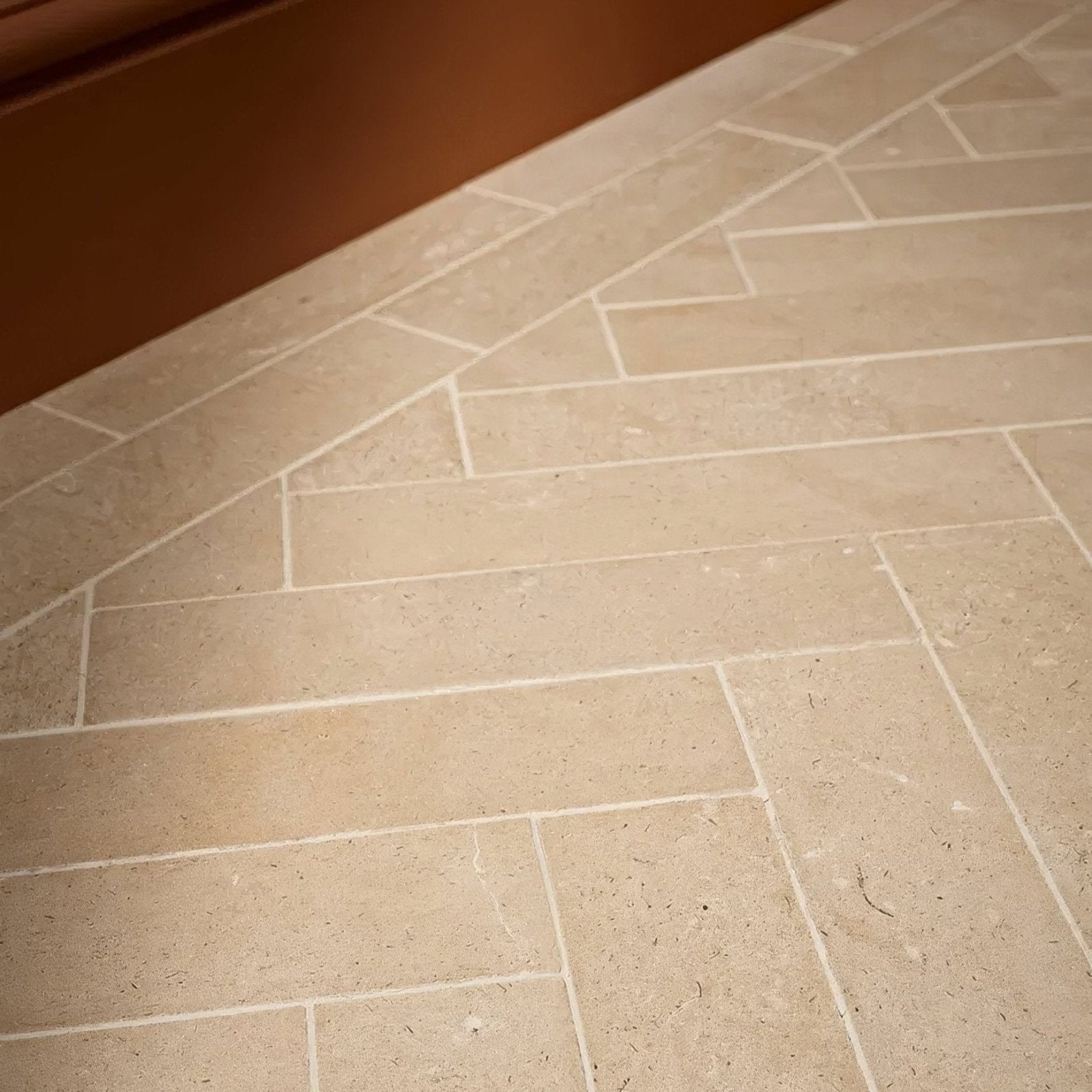 Beige stone tiles with subtle natural veining in a herringbone pattern portland limestone honed parquet flooring