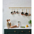A set of five copper pots with brass handles hanging from a gold-colored rod in pottery porcelain natural cotton brick style