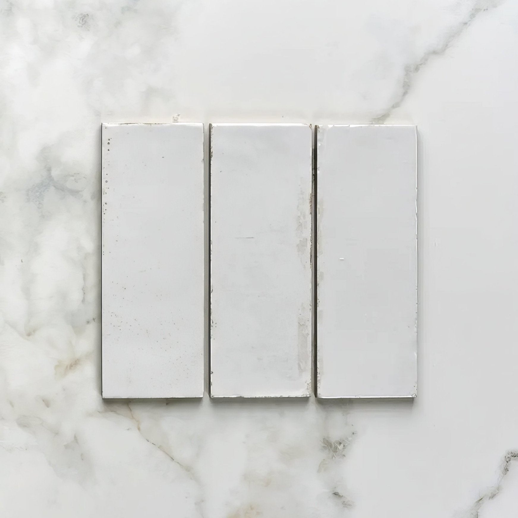 Three white rectangular porcelain tiles arranged side by side on a marble surface for pottery natural cotton brick