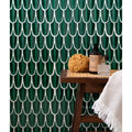 Deep emerald green porcelain fish-scale mosaic tiles with white grout lines create textured wall backdrop