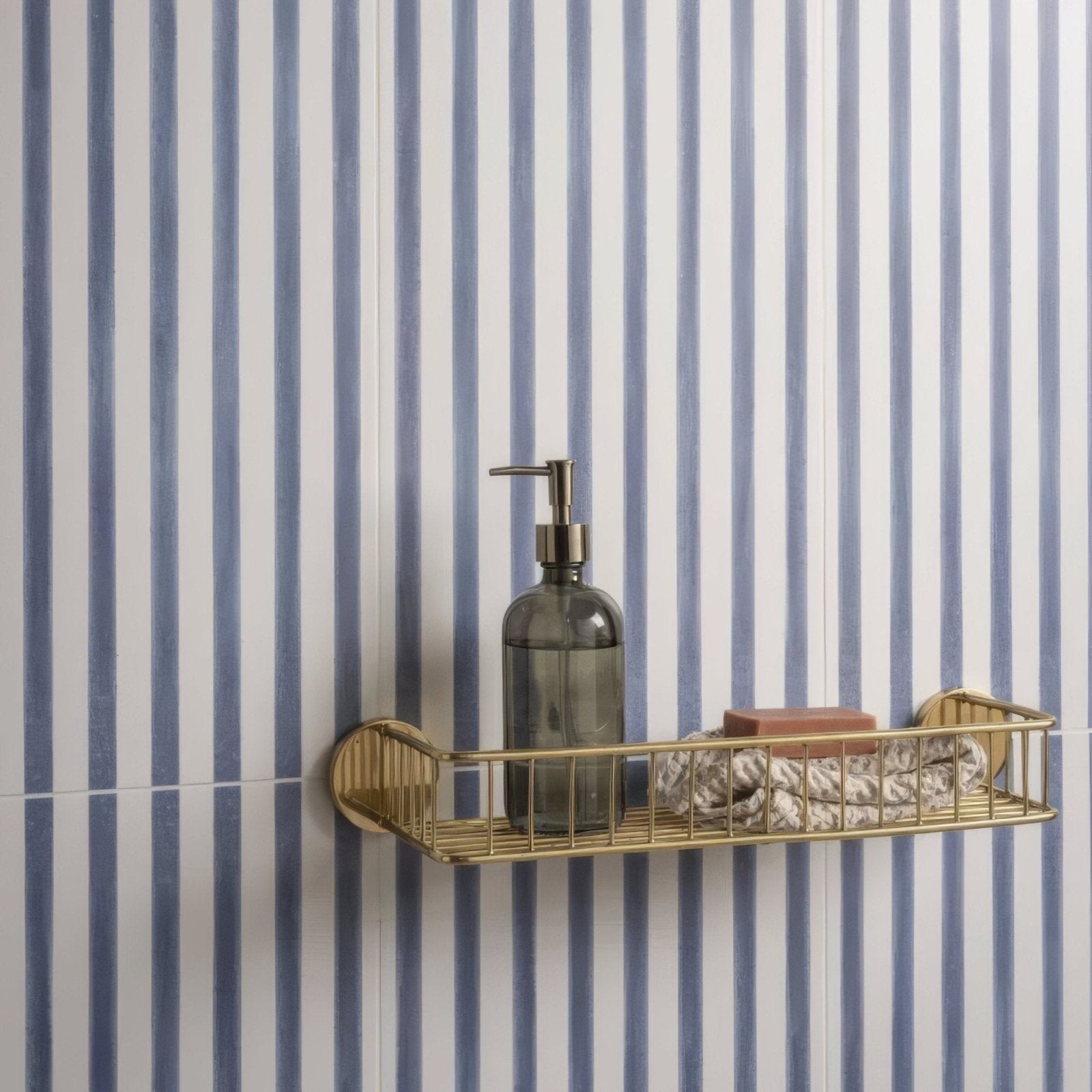 Promenade Brighton 60x30cm gold-toned wire shower caddy with a modern design holding a dark glass soap dispenser and towels