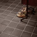 A pair of tan leather loafers with dark laces resting under a quarry black square tile table leg