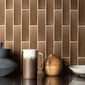 Brown ceramic pitcher with white glazed rim and handle displayed with quarry brick tile background