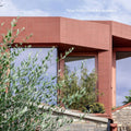 Modern red brick quarry red square tile building with large glass windows and green foliage in the foreground