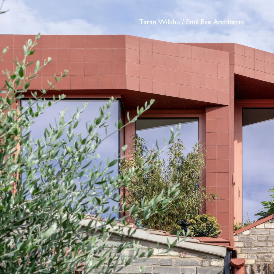 Modern red brick quarry red square tile building with large glass windows and green foliage in the foreground