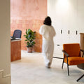 A woman walks through a modern space wearing a flowing white jumpsuit from Quintili Sand Opus