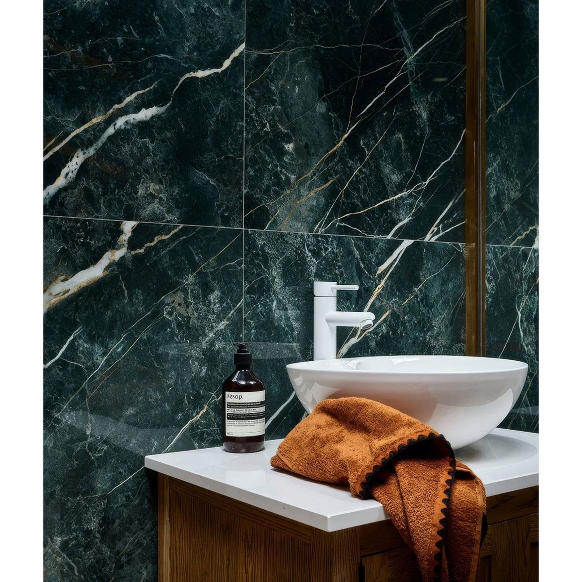 Rainforest Porcelain Malachite dark green marble-effect tiles with an amber glass bottle