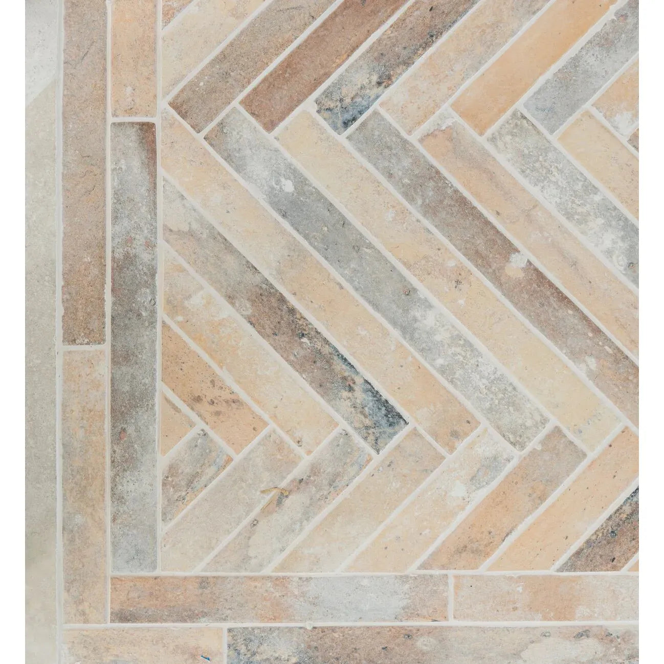 Beige and gray herringbone patterned ramsbury multi terracotta effect stone tiles with a rustic textured finish