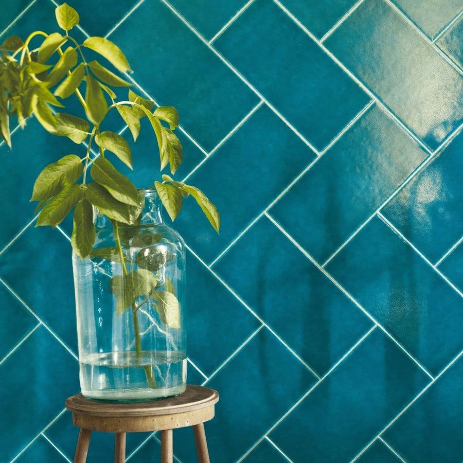 A clear glass jar with a wide mouth filled with water holding a green leafy plant stem from Ravello Frezza
