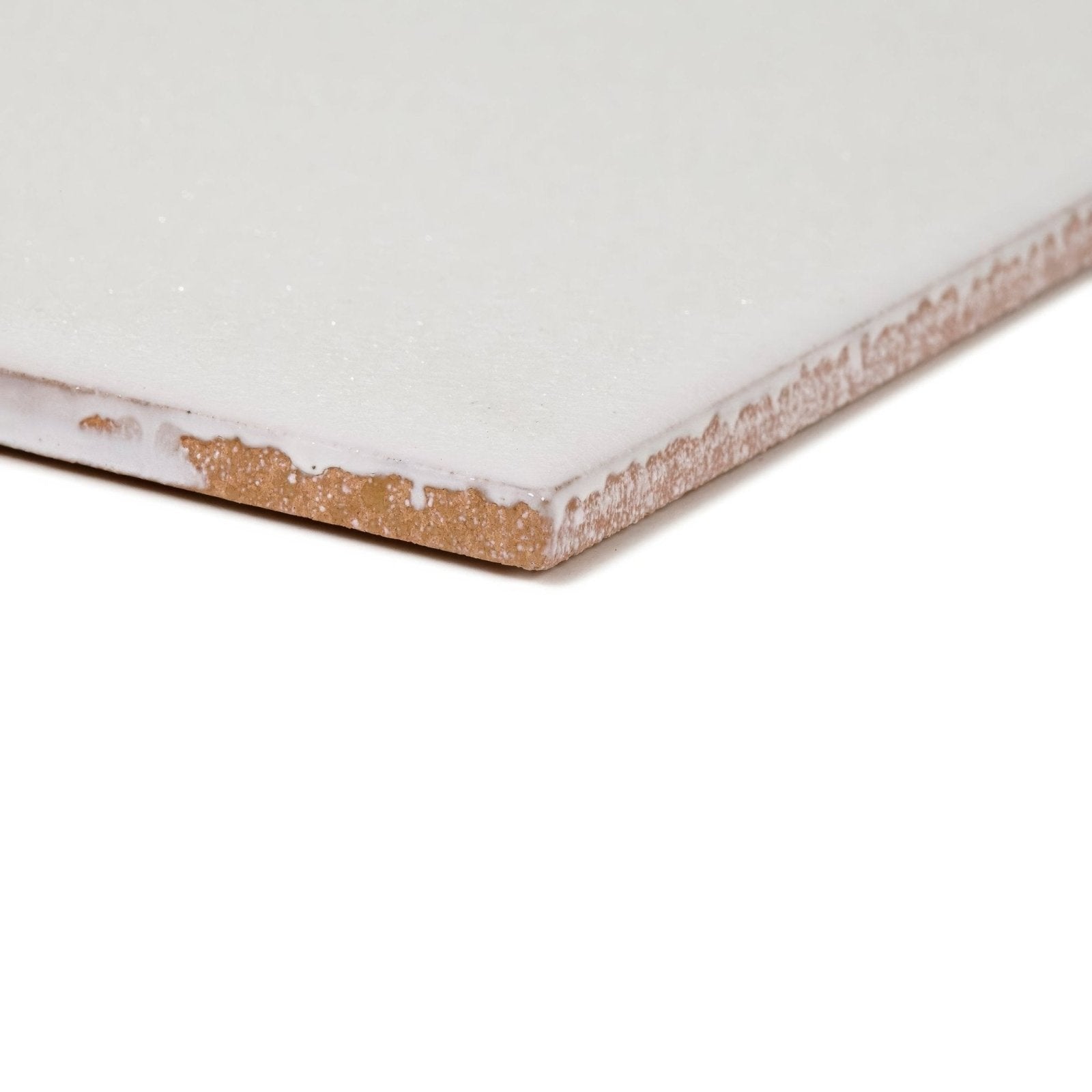 A white ceramic Ravello Grazie tile with a distressed rustic edge showing a textured brown backing backside view