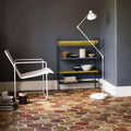 White metal floor lamp with adjustable arm and conical shade standing on reclaimed terracotta hexagonal tile floor
