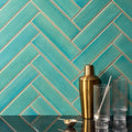 Golden metallic cocktail shaker with sleek cylindrical body and rounded top showcased with reef brick tile background