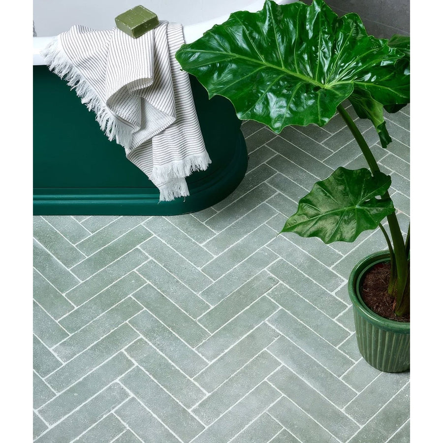Reform composite stone tumbled leaf green floor tiles in gray herringbone pattern with subtle white grout lines