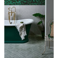 Deep emerald green freestanding Reform Composite Stone bathtub with white porcelain rim and gold-toned faucet fixtures