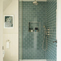 The retro metro green park glazed tile features sleek glossy teal subway tiles with a modern metallic finish in a shower