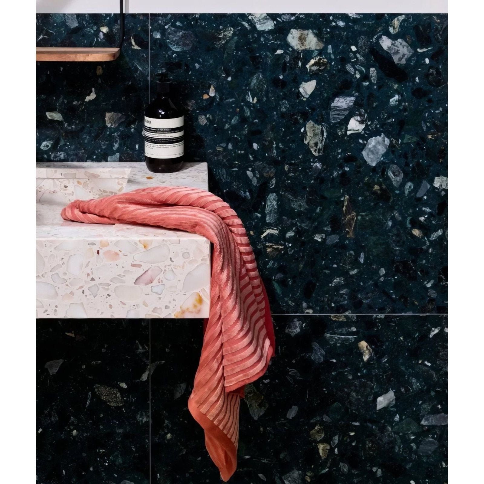 Rialto Terrazzo Foscari Honed dark green terrazzo tiles with a coral towel