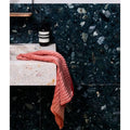 Rialto Terrazzo Foscari Honed dark green terrazzo tiles with a coral towel
