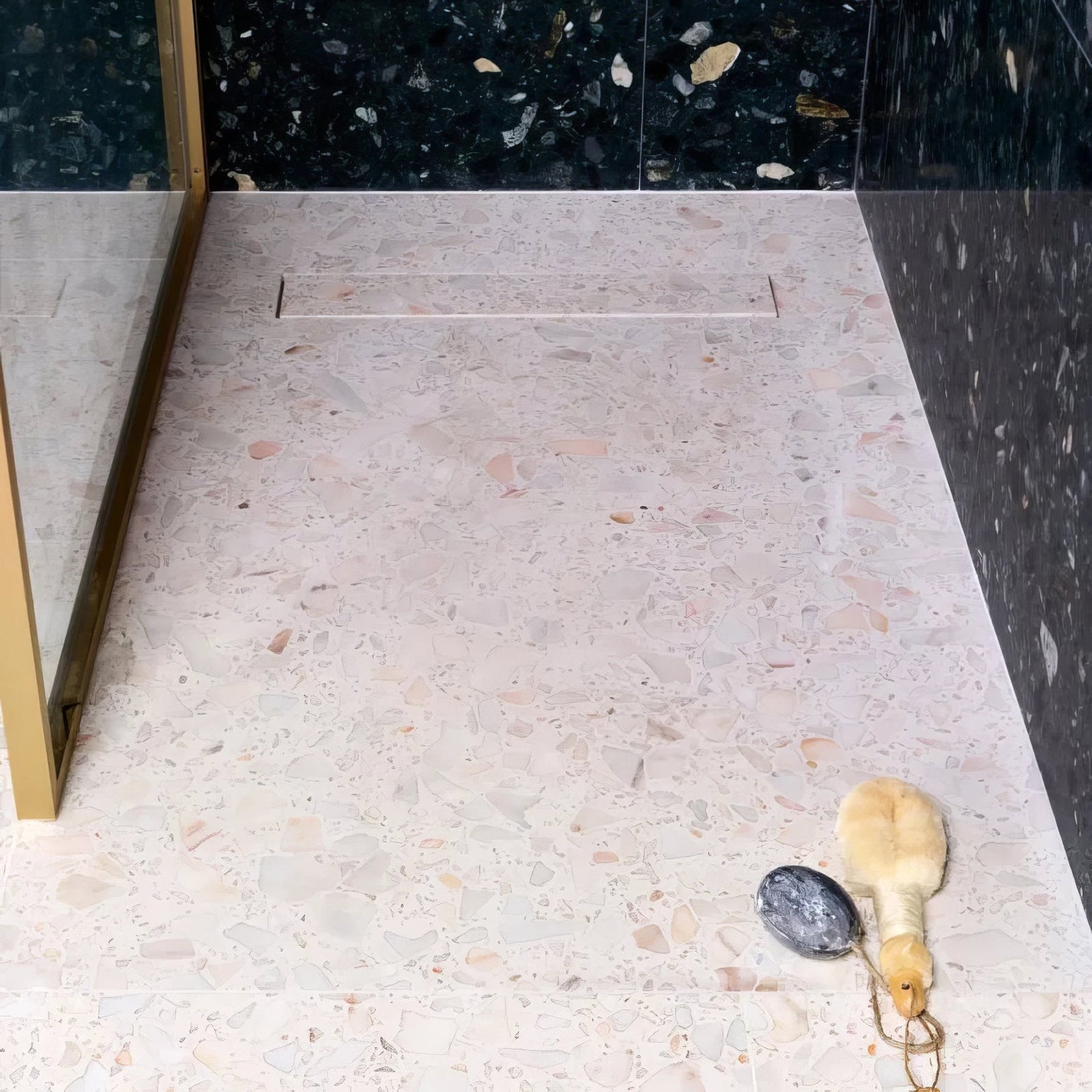 A soft pink rialto terrazzo veneta honed floor with gray and beige speckles bordered by dark green marble walls