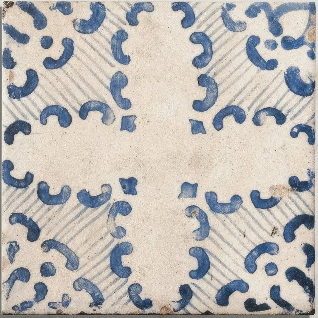 A square cream ceramic tile with hand-painted blue c-shaped motifs arranged diagonally from Sardinia Porcelain Tarricone