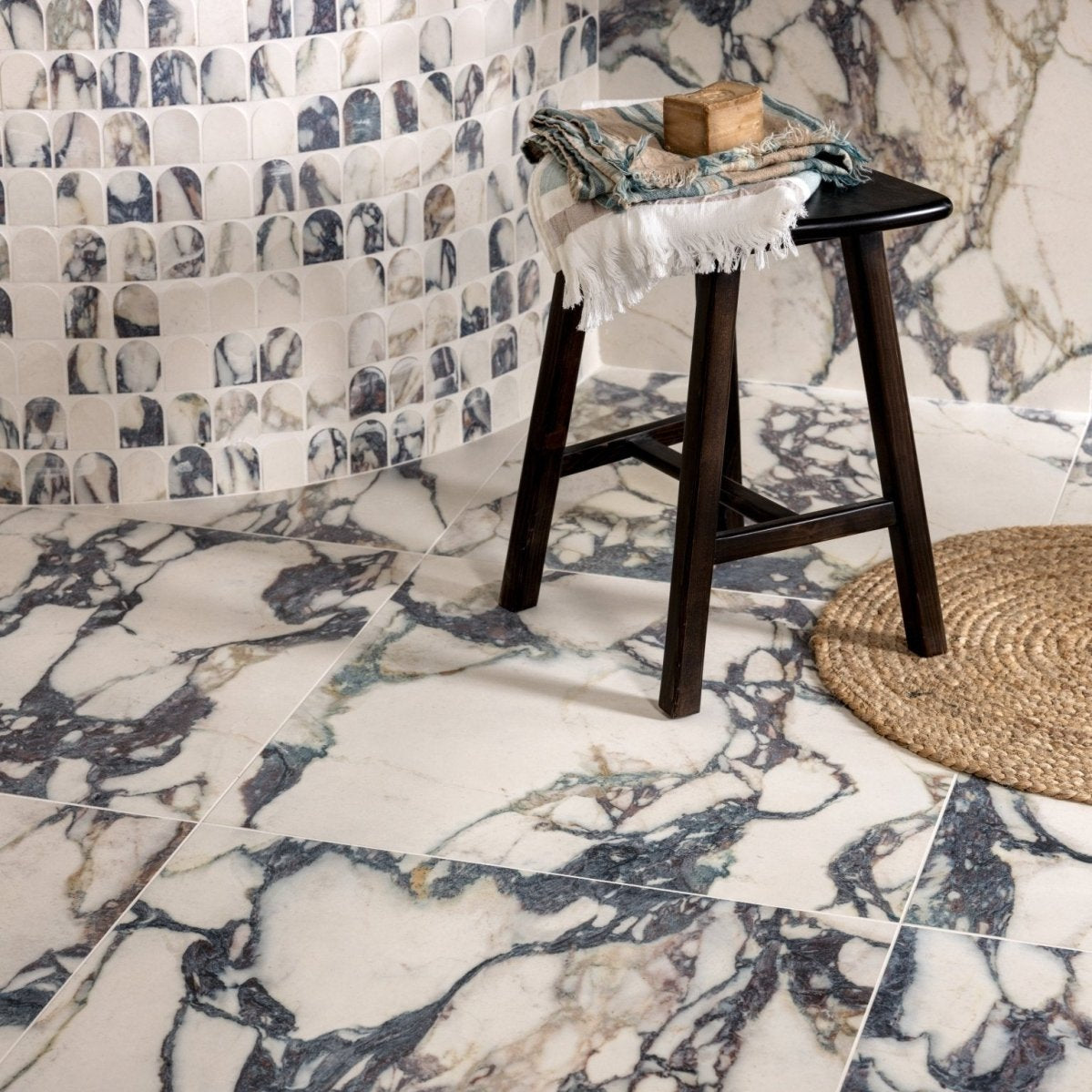 Dark wood stool with black seat and frayed white cloth draped over it for savoy novo porcelain matt arch mosaic display