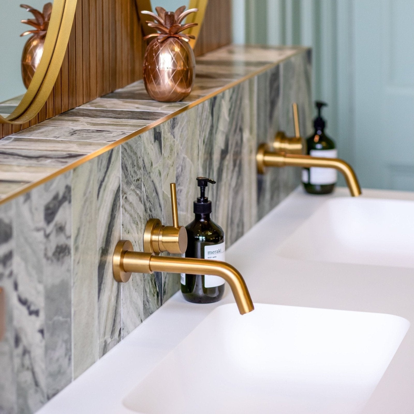 Gold-toned sleek modern faucet with brushed metal finish paired with seaspray green marble tile 10 x 30cm