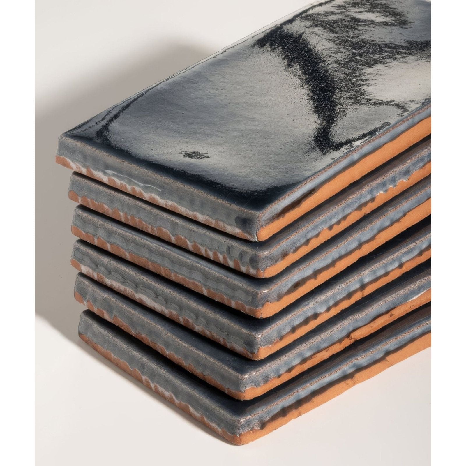 Stack of seaton ceramic beach hut rectangular tiles with glossy dark gray glaze and exposed terracotta edges