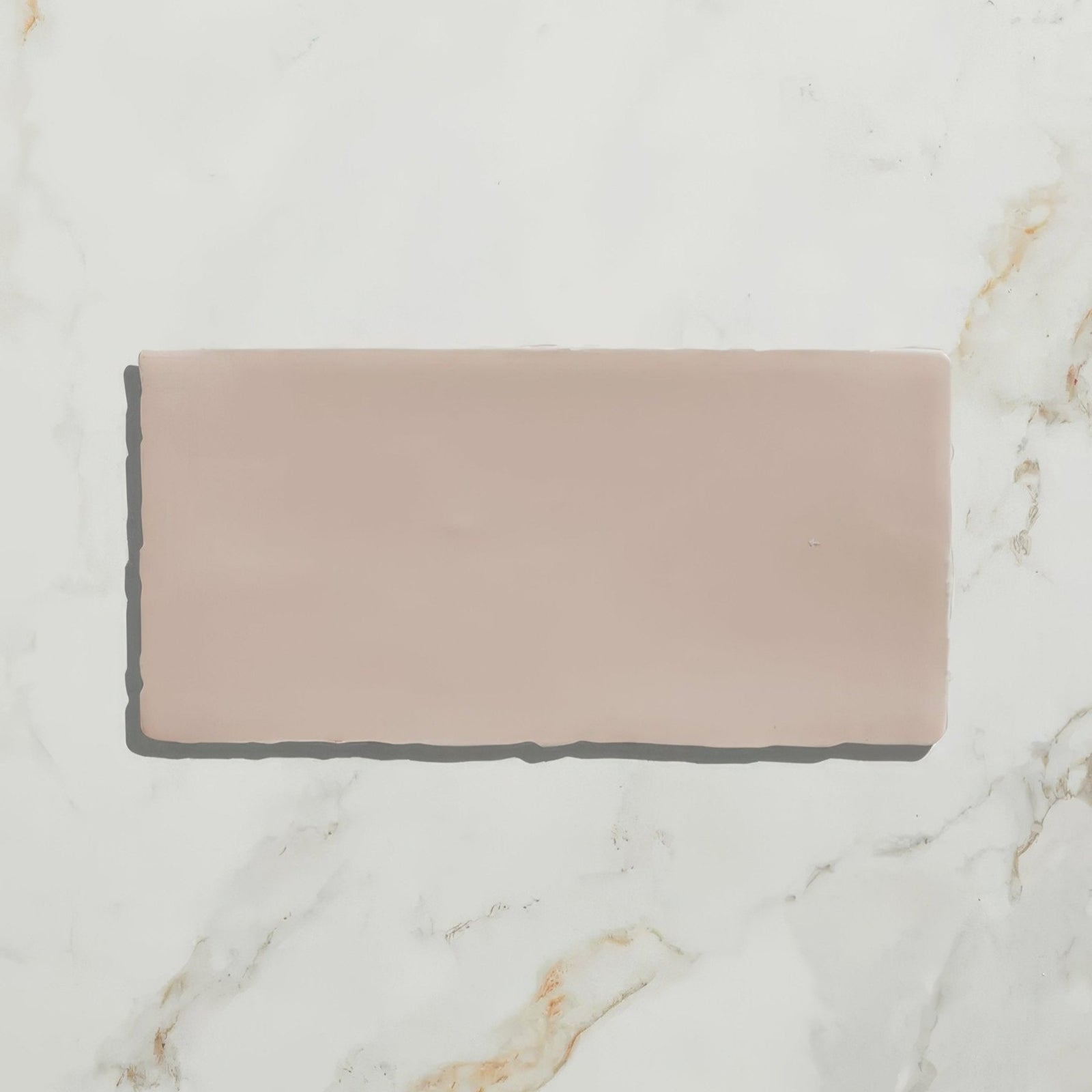 Seaton ceramic pink sands rectangular matte blush pink ceramic tile with slightly irregular edges on marble surface